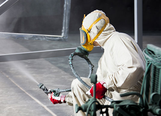 Un tecnico sta applicando vernice per l'industria a un telaio di ferro